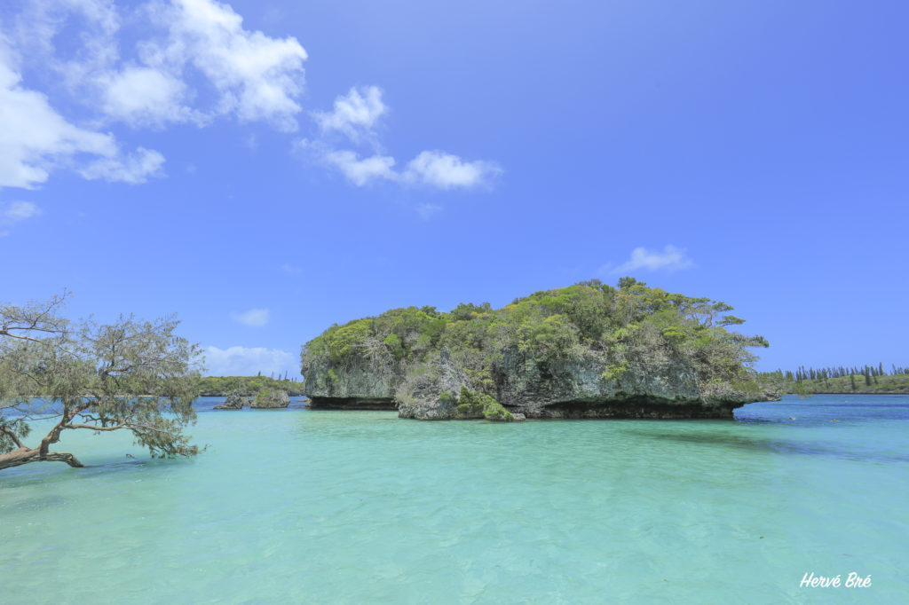 Baie de Kanuméra aux eaux turquoises et son îlot rocheux
